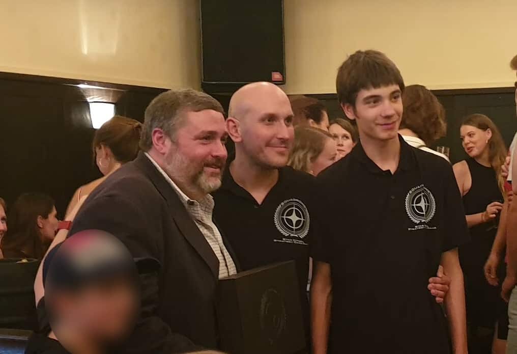 (Erin Roberts (left) being handed the Squadron prototype by Thomas Eberhard (centre) and son.)